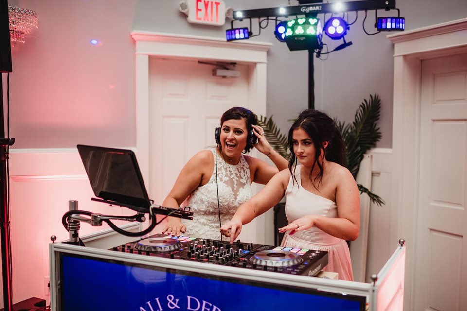 Two women are standing at a dj booth.